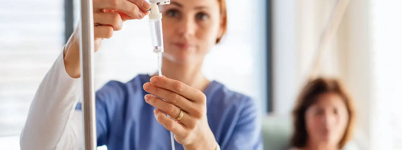 a-nurse-with-iv-drip-and-patient-in-bed-in-hospita-2024-10-21-09-29-24-utc